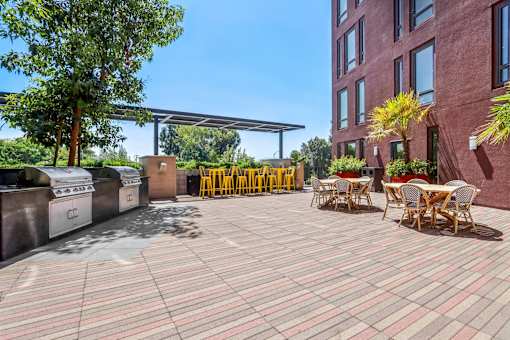 a patio with tables and chairs and a barbecue grill