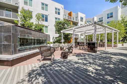 a patio with awnings and benches in front of an apartment building