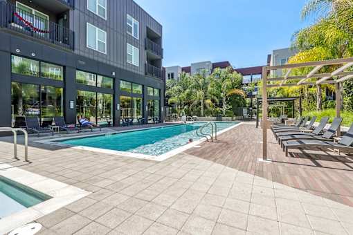 a swimming pool with lounge chairs in front of a building