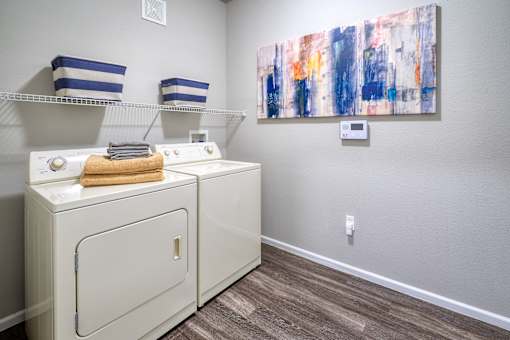 a washer and dryer in a laundry room with a painting on the wall