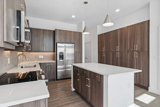 A modern kitchen with a white island and stainless steel appliances.