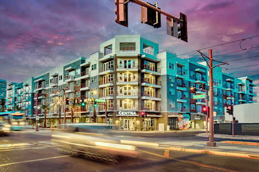 A street view of a city with a multi-story building with a sign that says "CENTRA" on it.