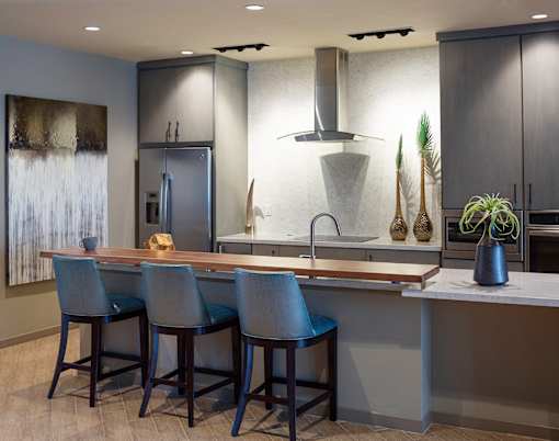 A modern kitchen with a bar area and chairs.