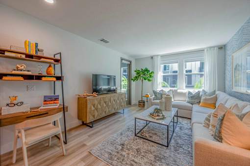 A living room with a white couch, a wooden chair, a coffee table, and a television.