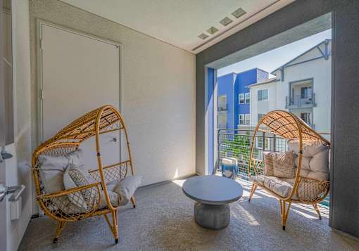A room with two wicker chairs and a table.