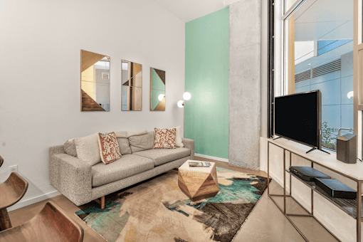 A living room with a grey couch and a rug.