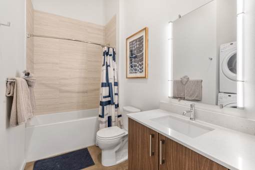 A modern bathroom with a white toilet, a white sink, and a white bathtub.