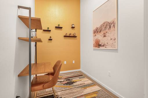 A room with a chair, a shelf, and a picture on the wall.