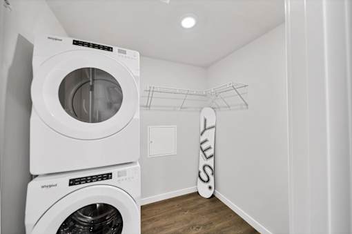 a white laundry room with a washer and dryer and a surfboard in