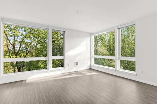 A large empty room with a view of trees through the windows.