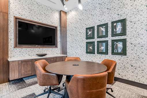 A conference room with a table, chairs and a television.