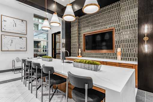 A modern kitchen with a white countertop and black chairs.