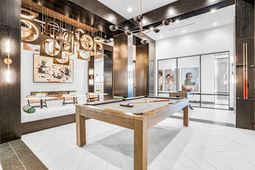A billiard table is in the middle of a room with a bench and a painting.