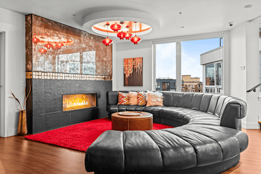 A modern living room with a black leather sofa and a fireplace.