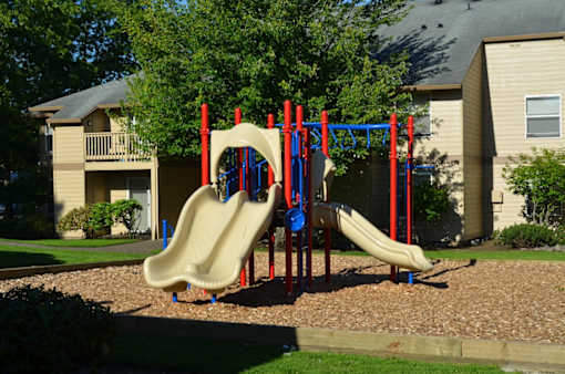 A playground with a yellow slide and red and blue poles.