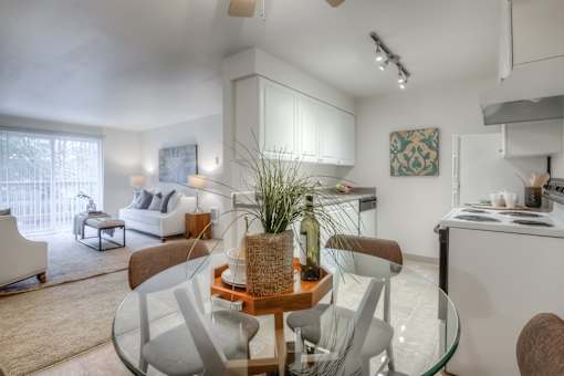 A modern living room with a glass dining table and chairs.