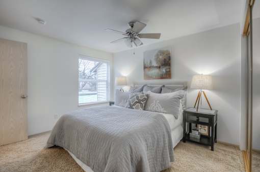 A bedroom with a bed, nightstand, and a ceiling fan.
