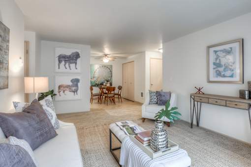 A living room with a white couch, a coffee table, and a painting of a bear on the wall.