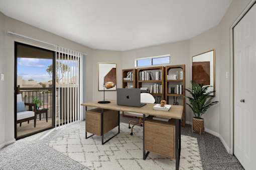 a home office with a laptop on a desk and a door to a balcony