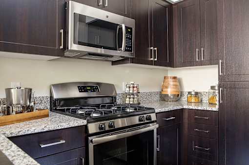 A modern kitchen with dark wood cabinets and stainless steel appliances.