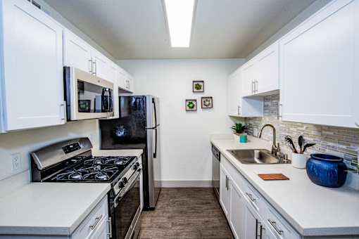 A kitchen with white cabinets and a black refrigerator.