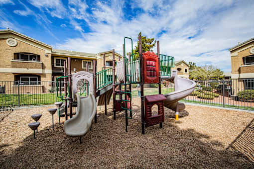 A playground with a slide, swings, and a seesaw.