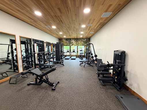 A gym with a variety of equipment including treadmills, weights, and exercise machines.