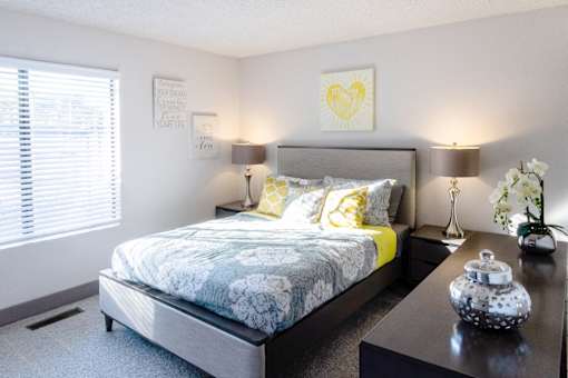 a bedroom with a bed and a night stand and a window