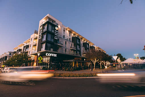A coffee shop is located in a modern building with a black awning.