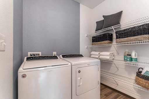 a laundry room with a washer and dryer and a shelf with towels
