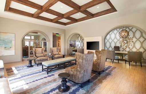 A living room with a large rug and a chandelier.
