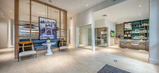 A modern living room with a large painting on the wall and a kitchen area in the background.