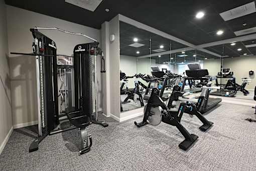 A gym with a variety of equipment including treadmills, weights, and exercise machines.