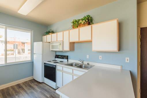 an empty kitchen with white appliances and a large window