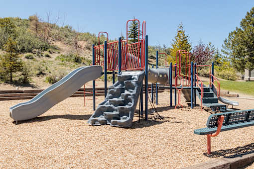 a playground with slides and benches in a park