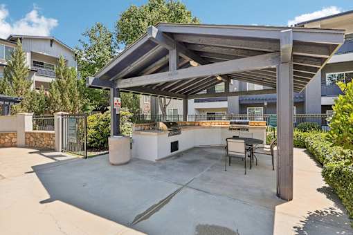 a patio with a grill and a table and chairs
