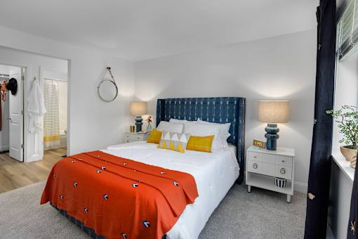 A bedroom with a white bed and orange bedspread.