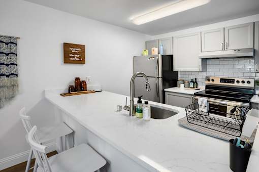 A kitchen with a white counter top and a stainless steel refrigerator.