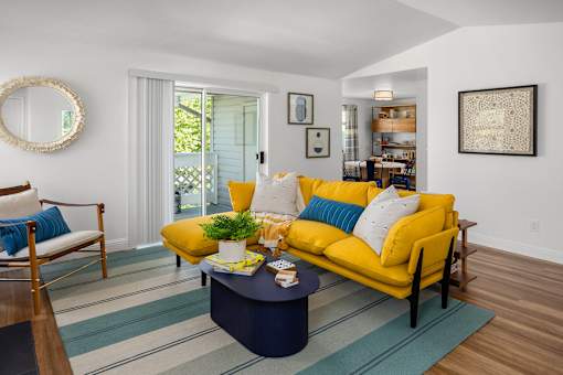 A living room with a yellow couch and a blue coffee table.