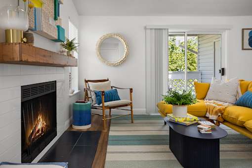 A living room with a fireplace and a yellow couch.