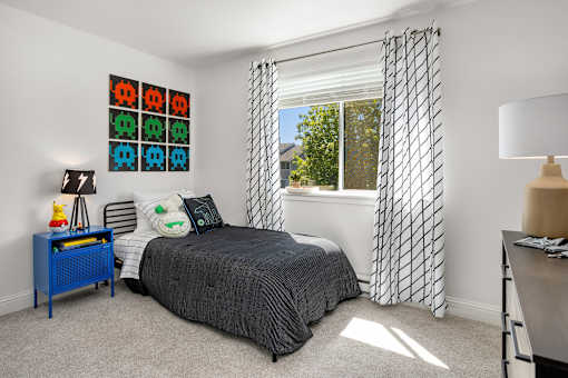 A bedroom with a bed, nightstand, and window with curtains.
