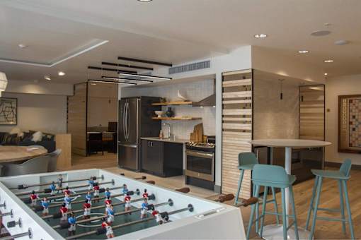 a game room with a foosball table and a kitchen
