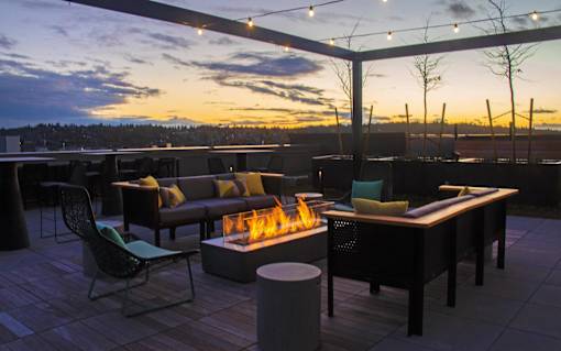 a rooftop patio with a fire pit and tables and chairs