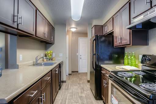 A kitchen with brown cabinets and a black refrigerator.