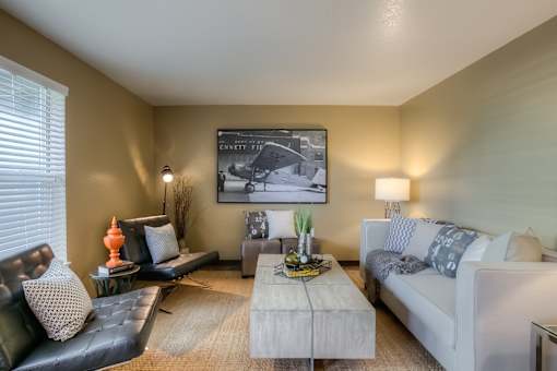 A living room with a white couch, a black leather chair, and a coffee table.