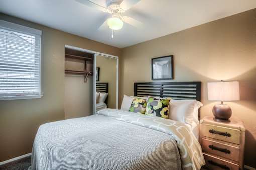 A bedroom with a bed, nightstand, and a ceiling fan.