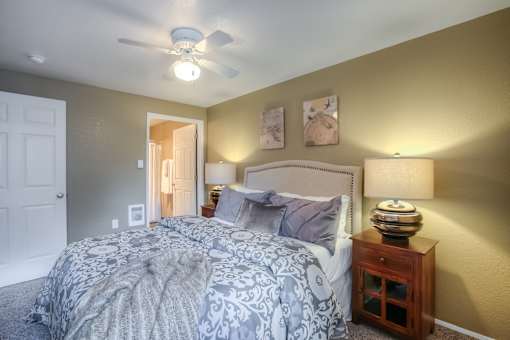 A bedroom with a bed, nightstand, and a ceiling fan.