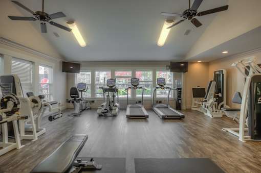 A spacious gym with a variety of equipment including treadmills, stationary bikes, and weight machines.