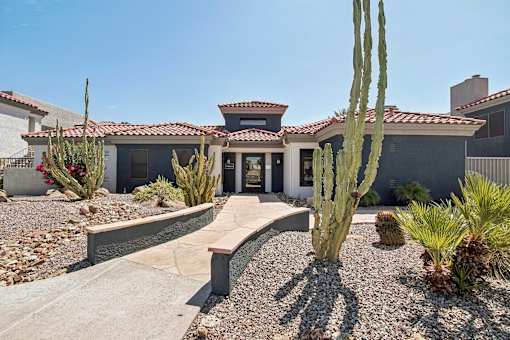 a house with a pathway and cactus in front of it