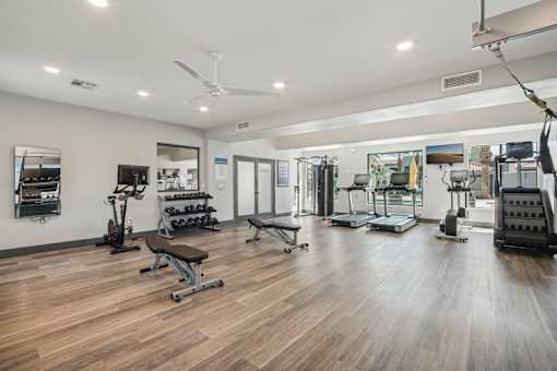 a fitness room with weights and cardio equipment on a wooden floor